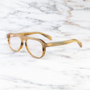 An image of the Cutler and Gross 0822V2 Aviator Horn Optical in Amber Buffalo Horn frame side view with arms open marble background