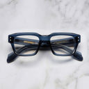 An image of the 1432 Square Optical in Deep Blue frame frontal view with arms closed marble background