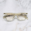 An image of the GR10 Square Optical Glasses in Butter Crystal frame frontal view with arms closed marble background 
