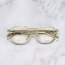 An image of the GR11 Round Opticals Butter Crystal  frame frontal view with arms closed marble background 