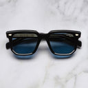 An image of the 1410 Square Polarised Sunglasses in Black frame frontal view with arms closed marble background