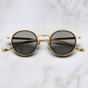 An image of the Cutler and Gross 1438 Round Horn Optical in Black/Gold frame frontal view with arms closed in marble background.