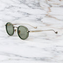 An image of the Cutler and Gross Brompton 1438 in Antique Green/Silver frame side view with arms open in marble background.