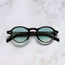 An image of the GR08 Round Sunglasses in Black frame frontal view with arms closed marble background 