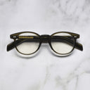 An image of the GR16 Round Opticals in Olive frame frontal view with arms closed marble background