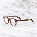 An image of the GR16 Round Opticals in Havana frame side view with arms open marble background