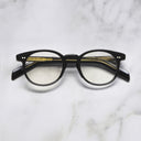 An image of the GR16 Round Opticals in Black frame frontal view with arms closed marble background