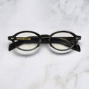 An image of the GR13 Oval Opticals in Black Horn frame frontal view with arms closed marble background
