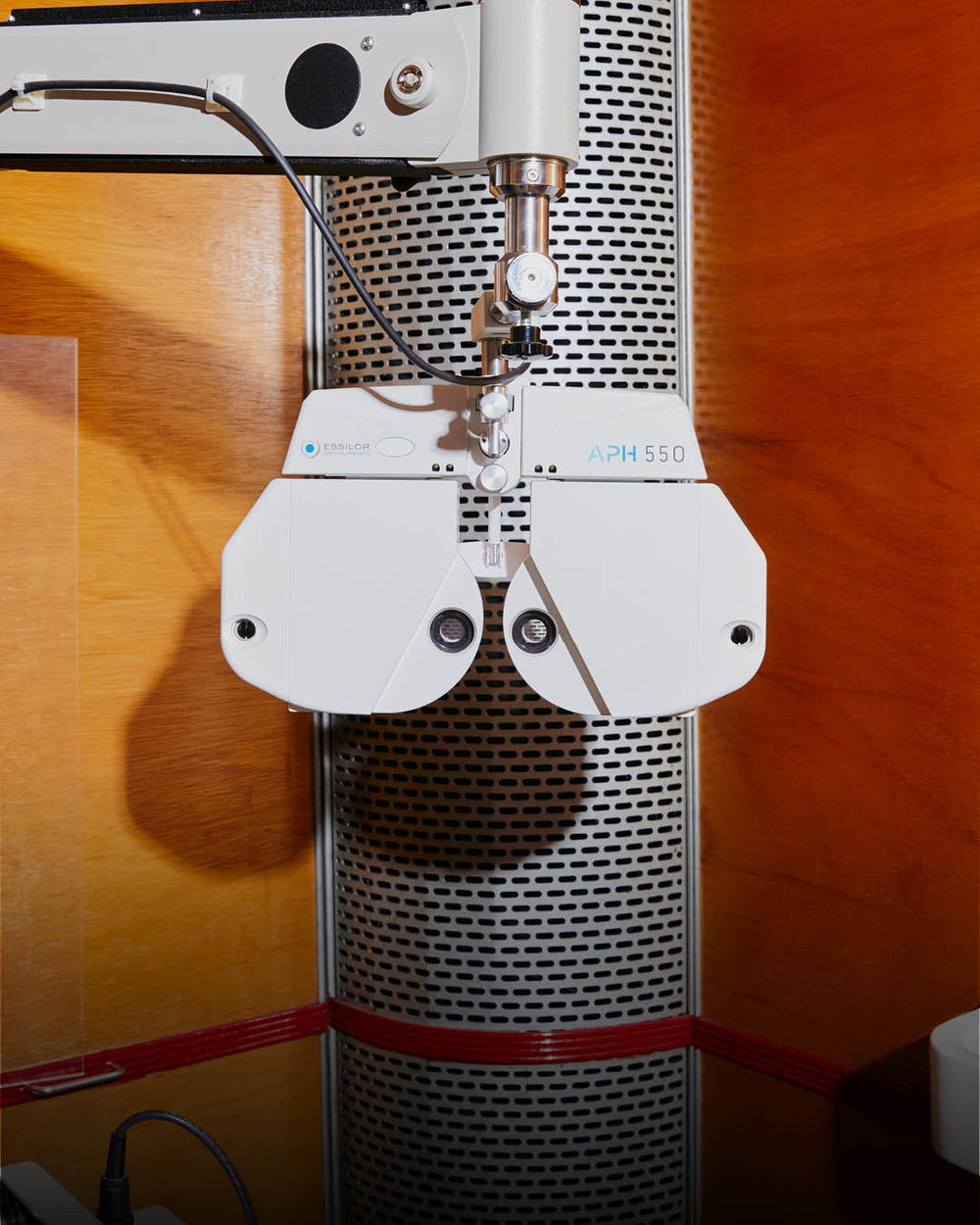 An Image of Optical equipment in a clinical setting with wooden walls. This image is titled as Eye Exam ,  fully clickable and linking to eye exam booking page.