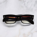 An image of the The Great Frog Dagger Square Optical Glasses in Black frame frontal view with arms closed marble background 