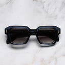 An image of the The Great Frog Bones Link Rectangle Sunglasses in Deep Blue frame frontal view with arms closed marble background 