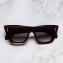 An image of the The Great Frog Love And Death Cat Eye Sunglasses in Bordeaux frame frontal view with arms closed marble background 