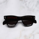 An image of the The Great Frog Phantom Square Sunglasses in Black on Red frame frontal view with arms closed marble background 