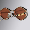 Close up still life image of the Great Frog Carol sunglasses from left side view with orange lenses and gold skull details on the temples